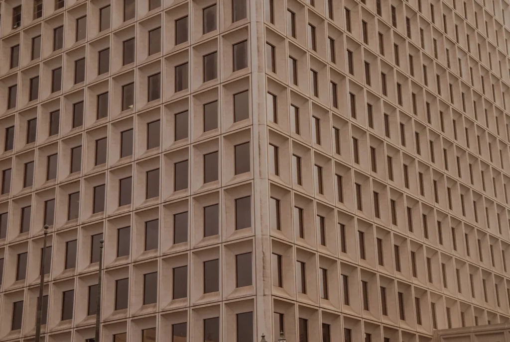 Tall building with many windows and a clock tower in the background