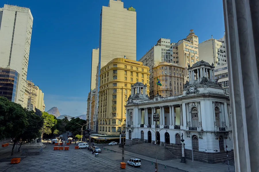 Bustling city street in Rio de Janeiro, Brazil, with tall buildings, vehicles on the road, light poles, trees