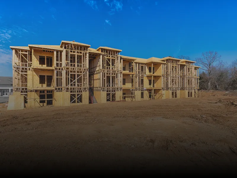 New home under construction in the middle of a dirt field, with wooden sticks framing the building