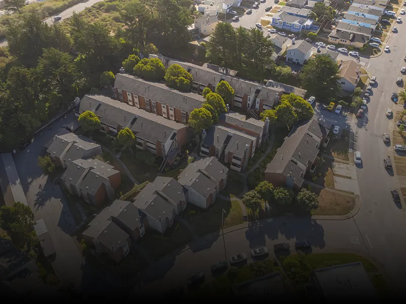 Aerial view of a residential neighborhood in, California, with a row of houses, trees, and vehicles on the road