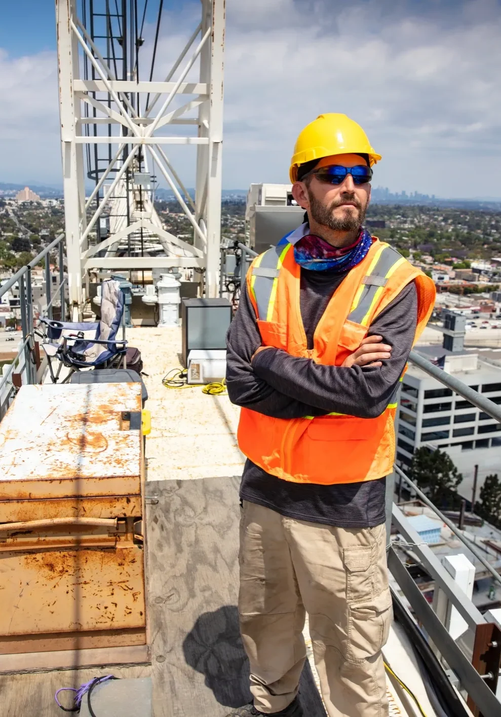 Man in a hard hat and safety vest standing on top of a building, surrounded by iron rods