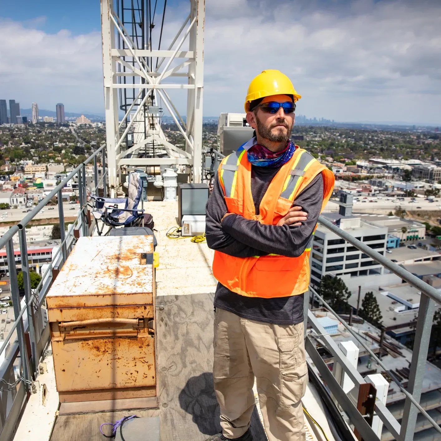Man in a hard hat and safety vest standing on top of a building, surrounded by iron rods